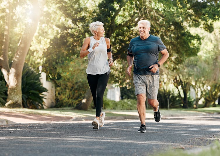 A middle-aged couple running in a park.