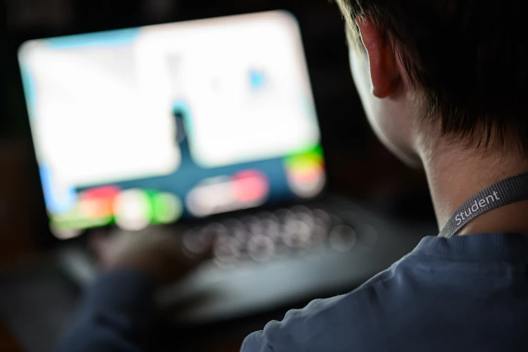 teen looking at laptop in the dark