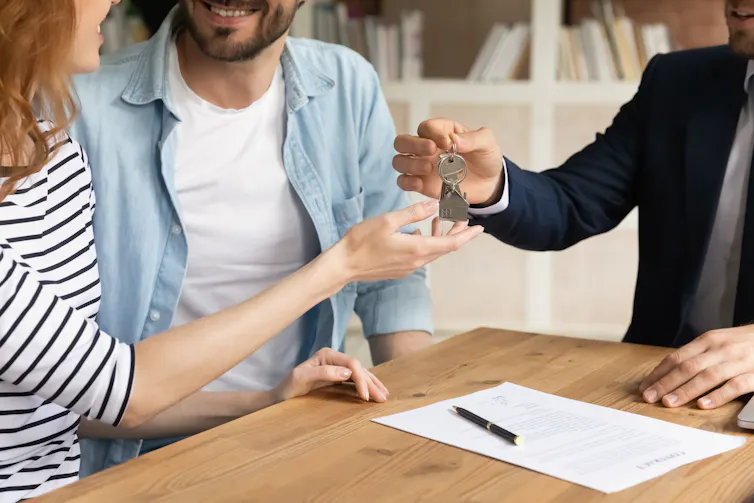 Man in suit handing keys to a woman and man