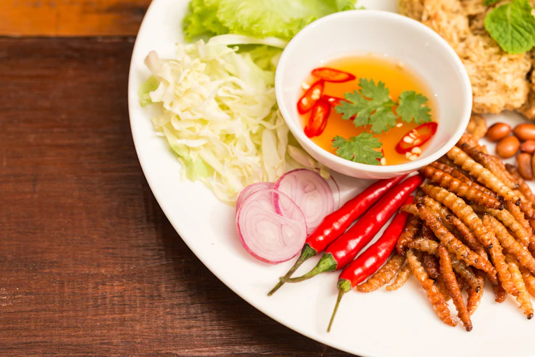 A selection of vegetables and a dip with fried bamboo worm