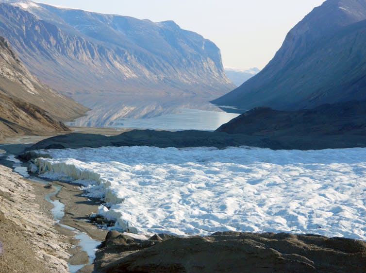 An area with ice cover in the foreground, and mountains in the background.