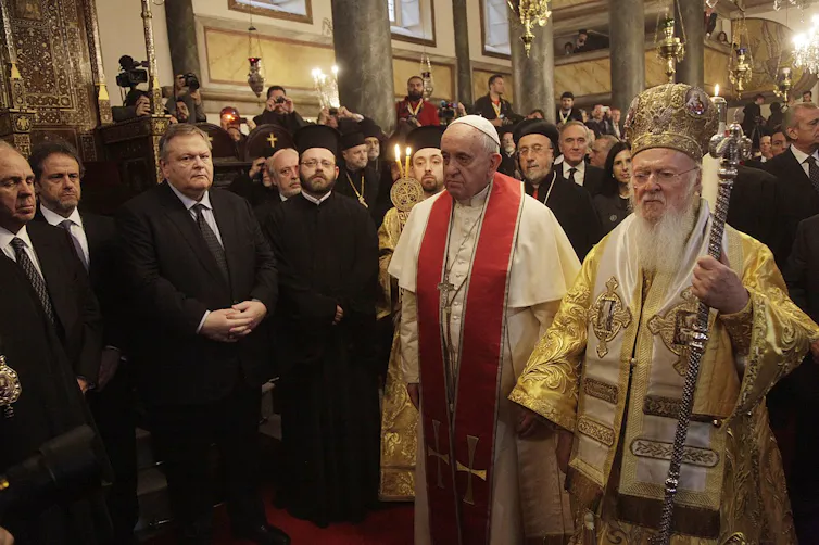 Dos hombres vestidos con casacas elegantes presiden una celebración religiosa.