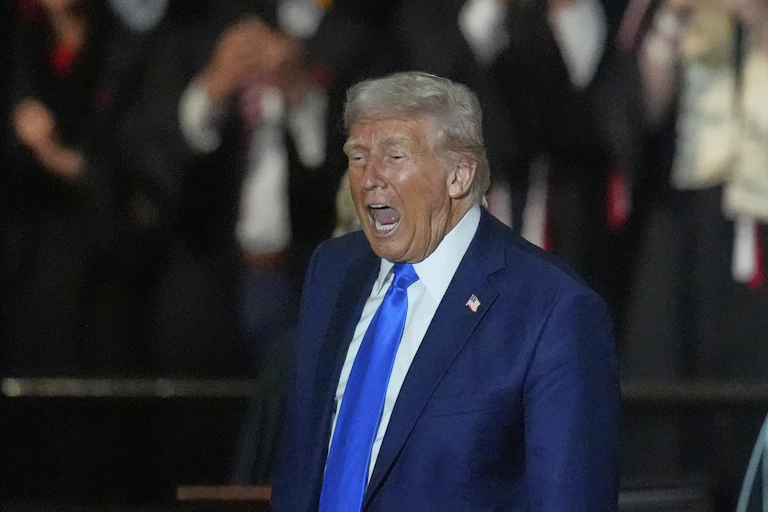 a man with heavy facial bronzer in a suit with his mouth wide open