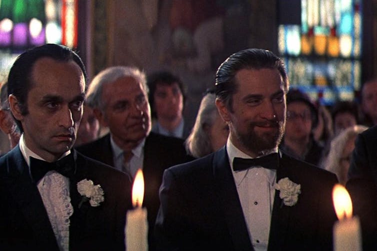 Dos hombres de traje sonríen en una boda.