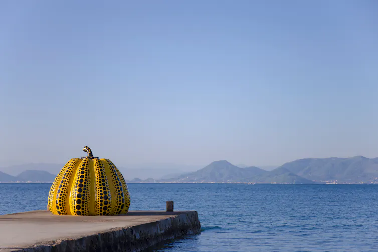 A big yellow pumpkin at the end of a dock.
