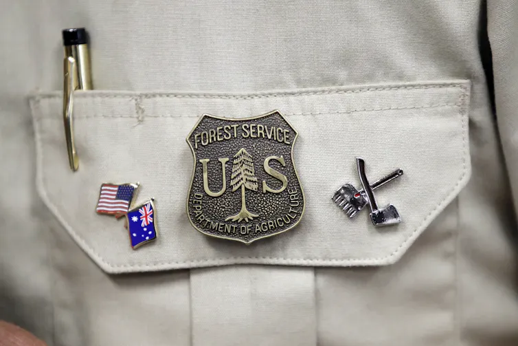A US Forest Service badge with two pins showing US and Australian flags.