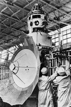 Two scientists work on a spacecraft.