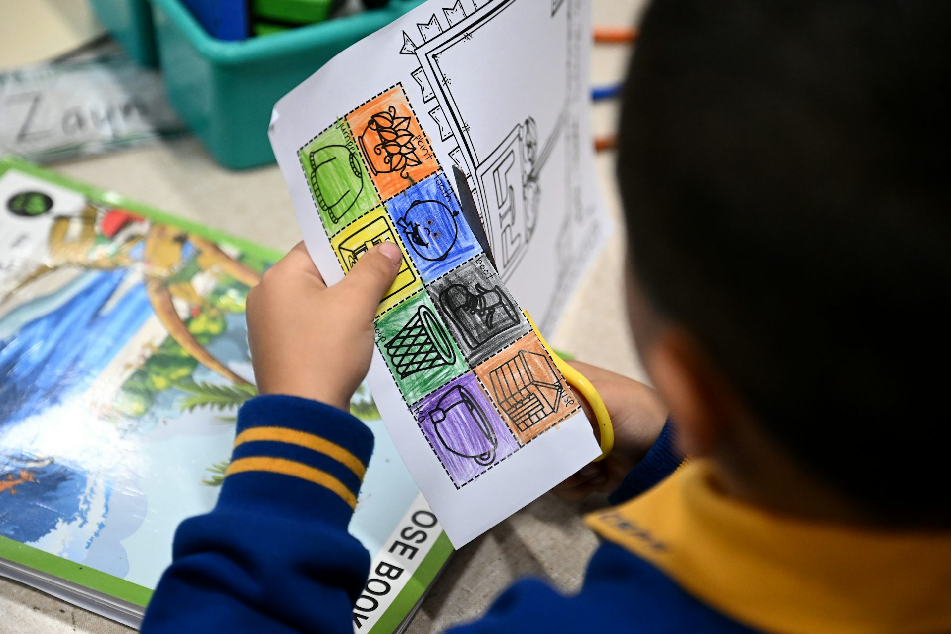 A young student cuts a sheet of paper.