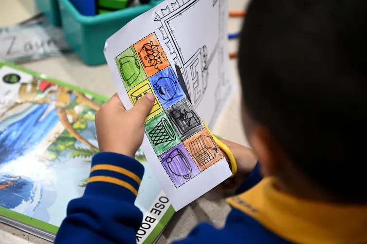 A young student cuts a sheet of paper.