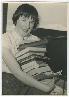 Young Beatrice carrying a stack of books.