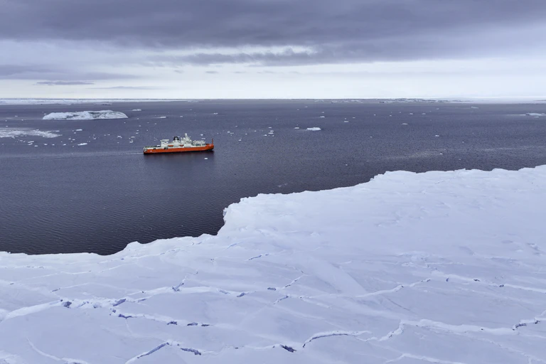 A ship cruising in the icy waters around Antarctica, as seen from the frozen continent.