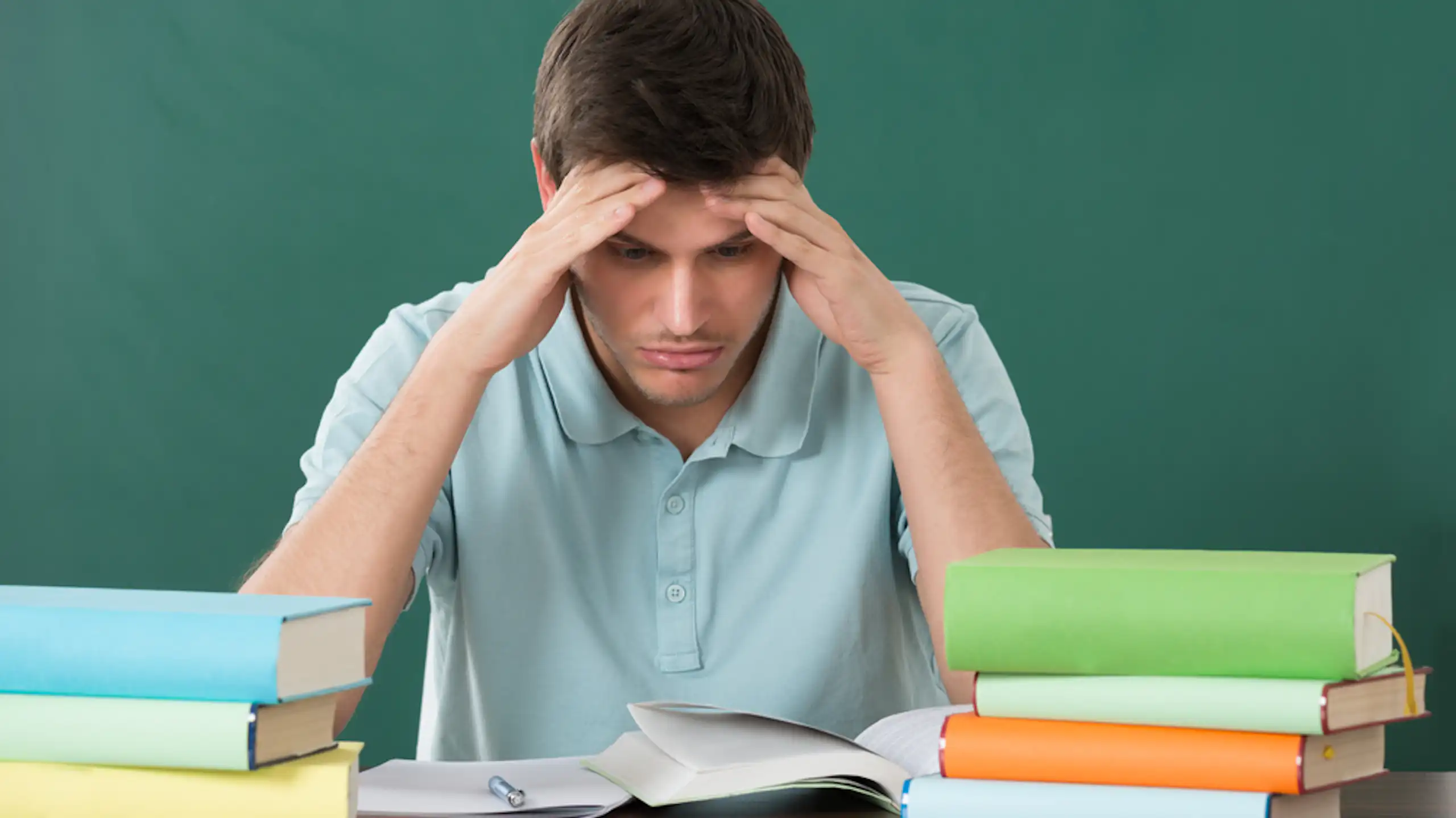 Un enseignant assis à son bureau devant une pile de dossiers.