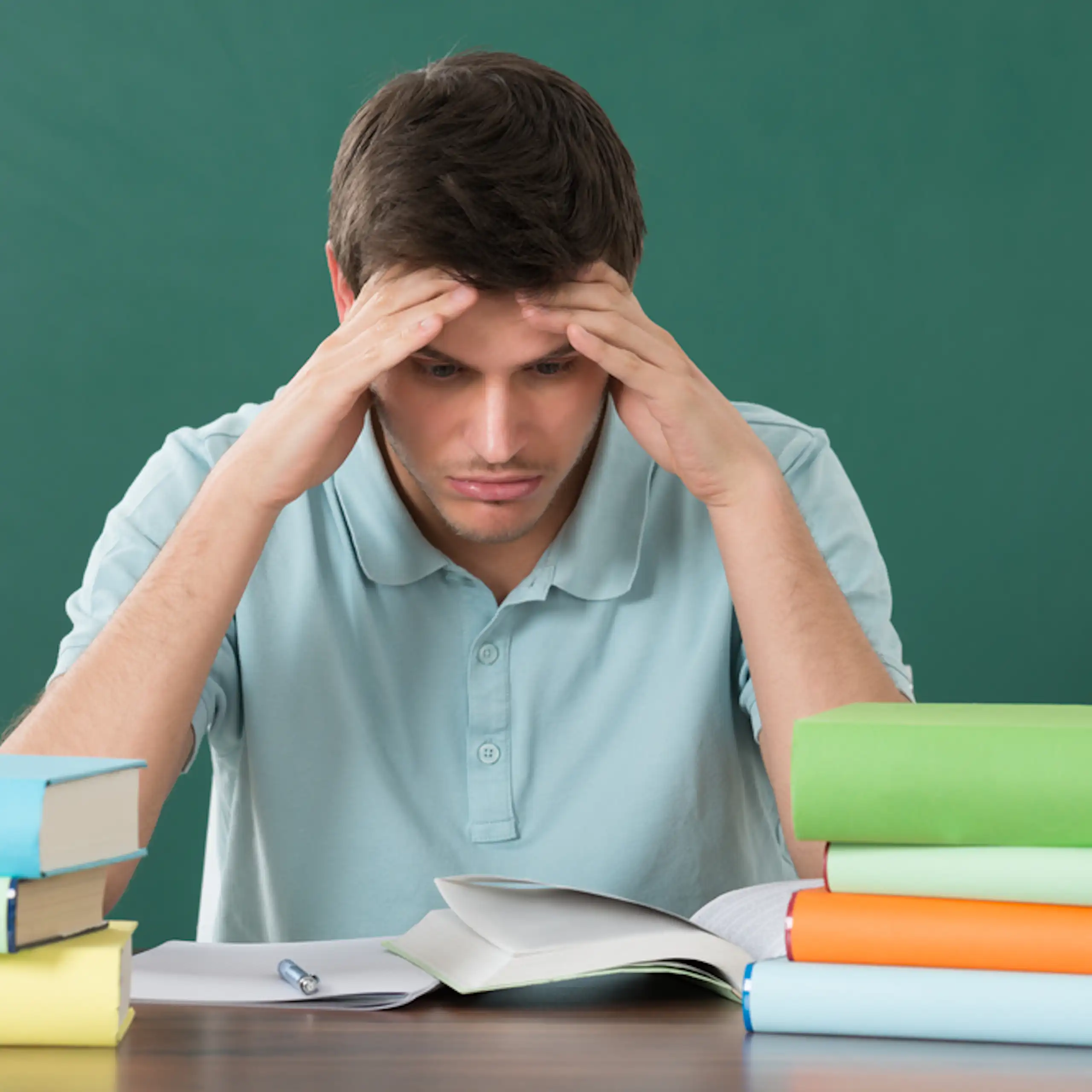 Un enseignant assis à son bureau devant une pile de dossiers.