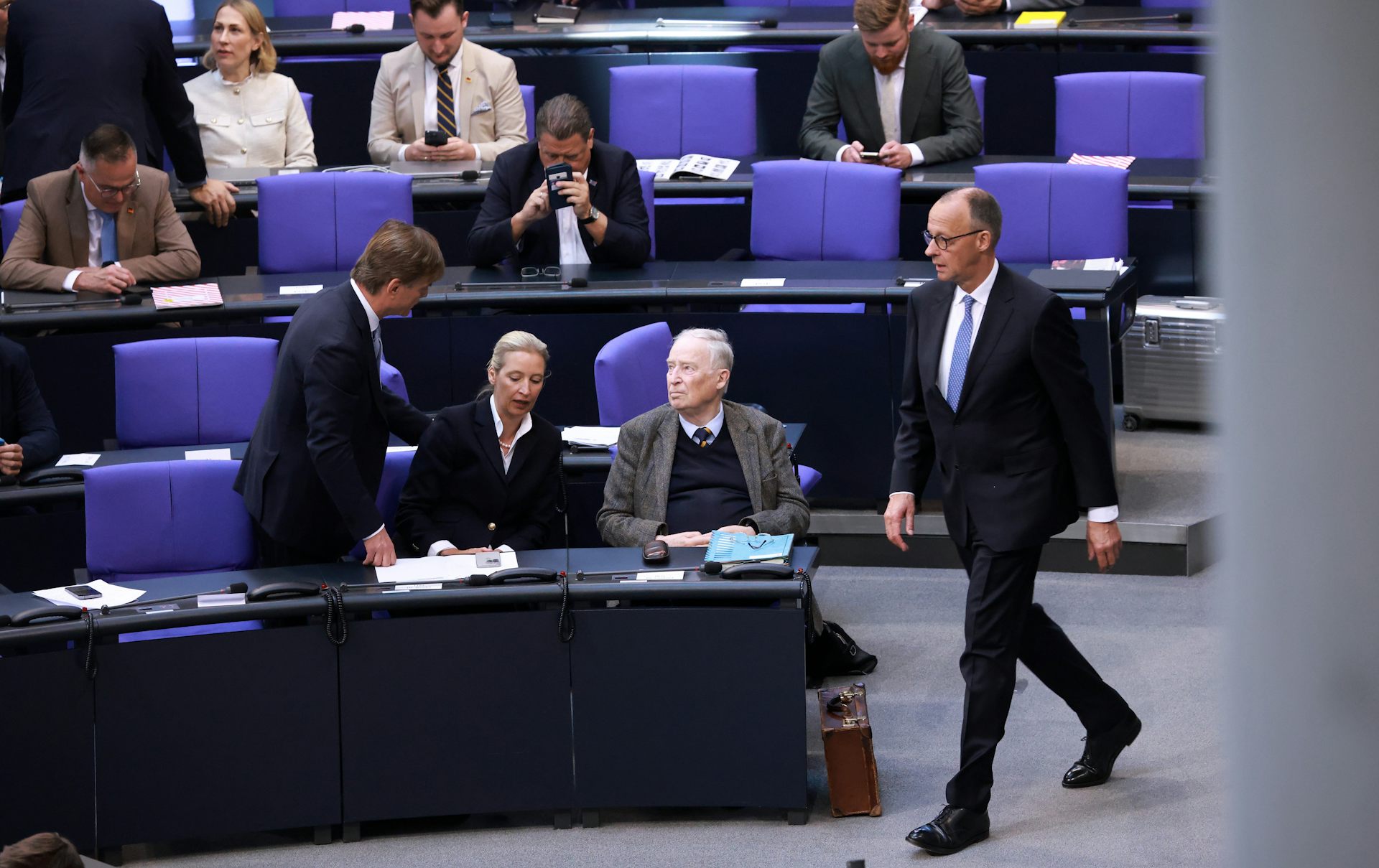 Friedrich Merz walking in front of seated members of the AfD in the German parliament.
