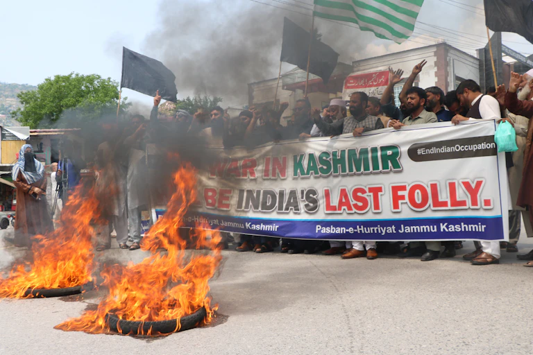 Anti-India protesters carry a banner and burn tyres in Pakistan.
