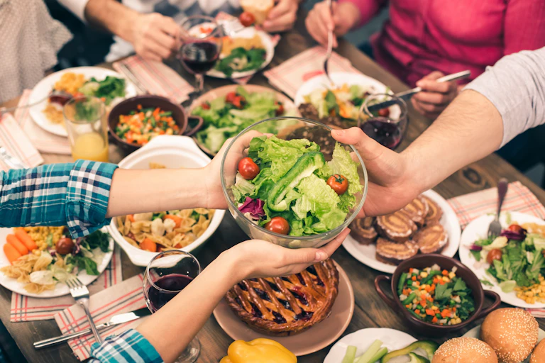 Photo of a dinner table with people out of frame passing a salad bowl