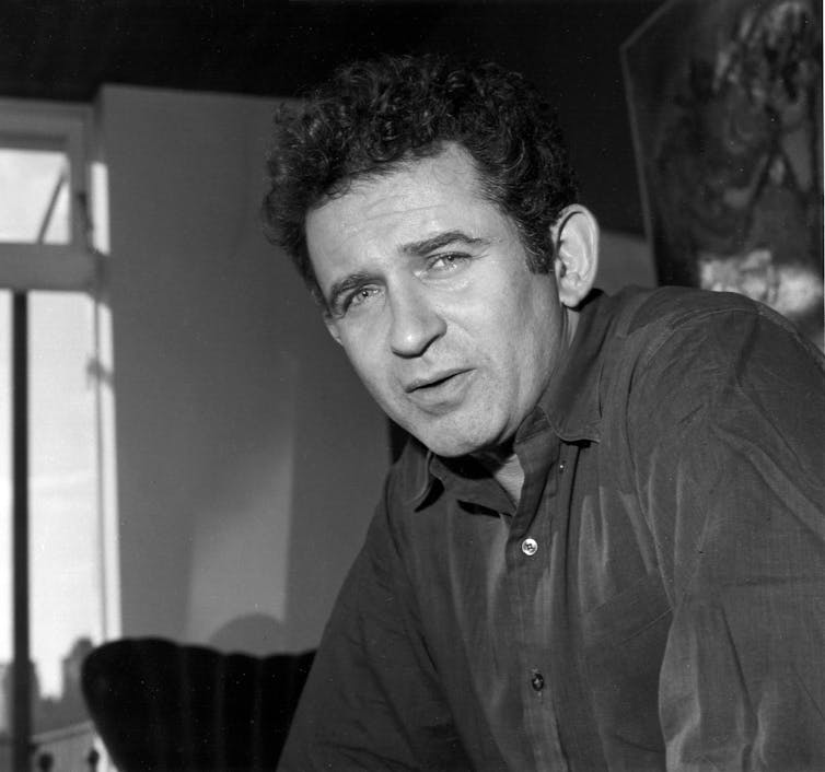 A man with curly dark hair in a button down shirt.