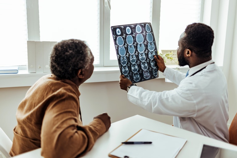 A male doctor and patient examine a brain MR scan