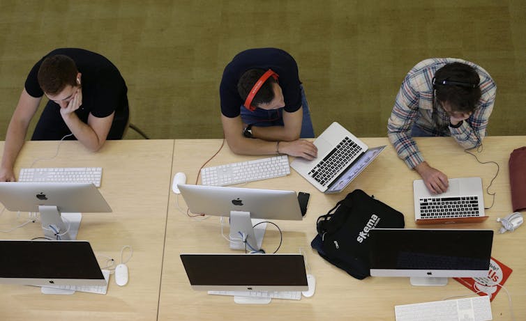 Estudiantes sentados en una mesa larga vista en la descripción general, uno mira a otro.
