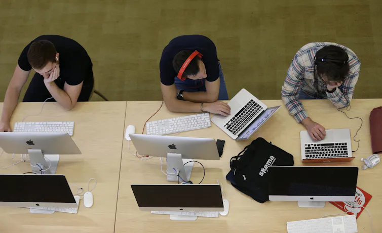 Students sitting at a long table seen in overhead view, one is looking over at the other.