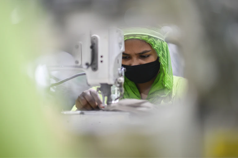 A woman stitches a garment at a factory