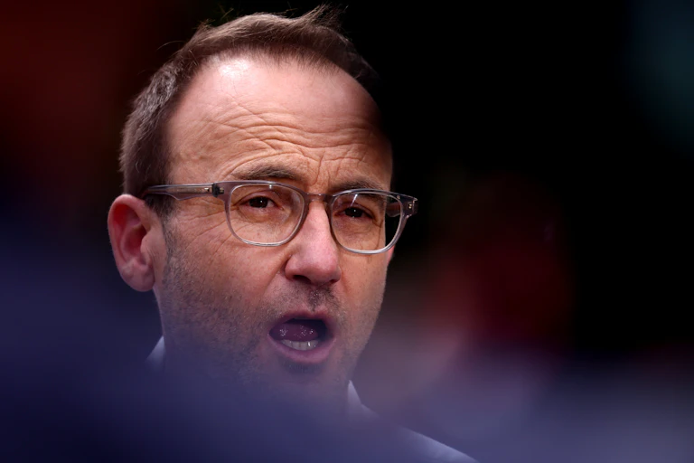 The partially obscured face of a man wearing glasses