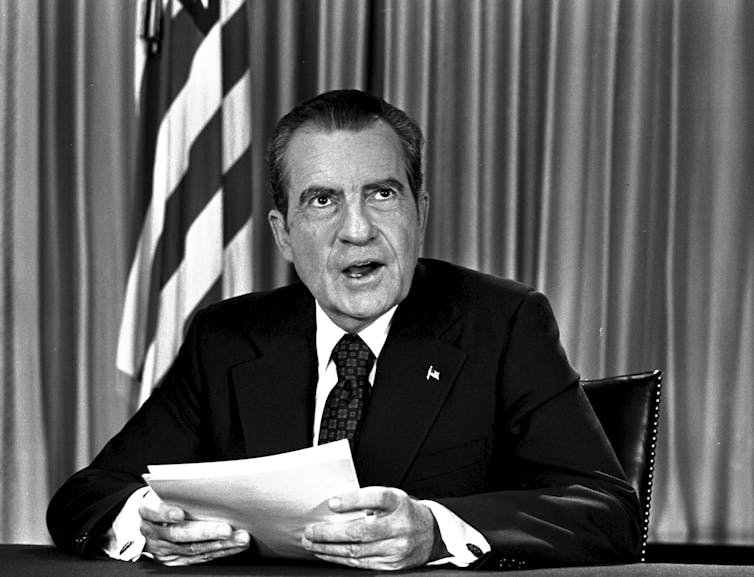A black and white photo of a man holding papers.
