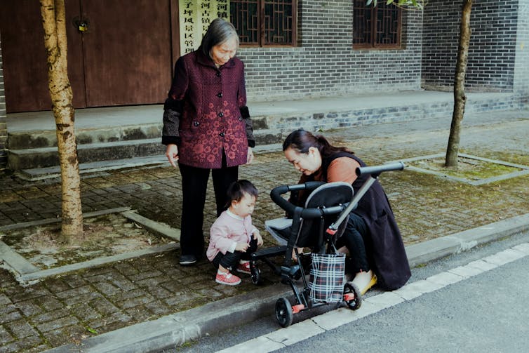 A baby, a mother and a grandmother on the footpath.