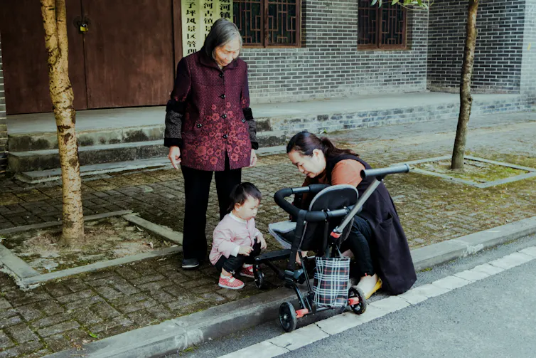 A baby, a mother and a grandmother on the footpath.