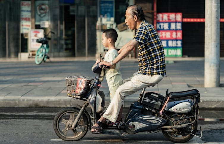 A grandfather and his grandson speed through the streets on a bike.