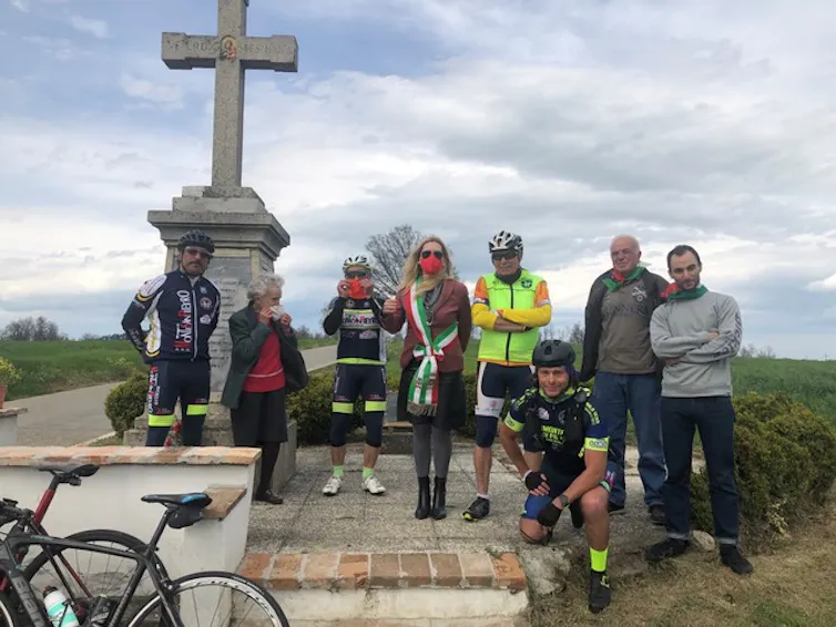 A group of cyclists standing in front of a monument.