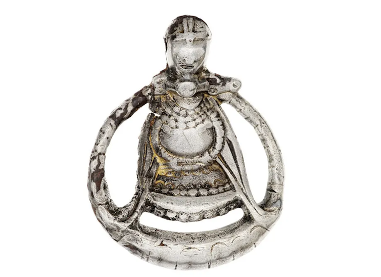 A silver pendant showing a pregnant woman
