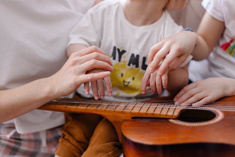 For kids with a unprecedented type of dementia, track is usually a tough treatment software 1 A child plays the guitar with the help of two adults.
