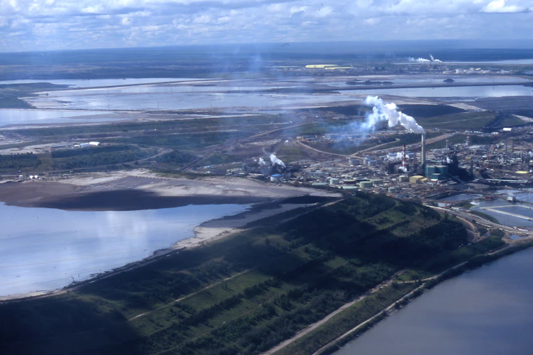 An aerial view shows two oilsands facilities in an expansive landscape.