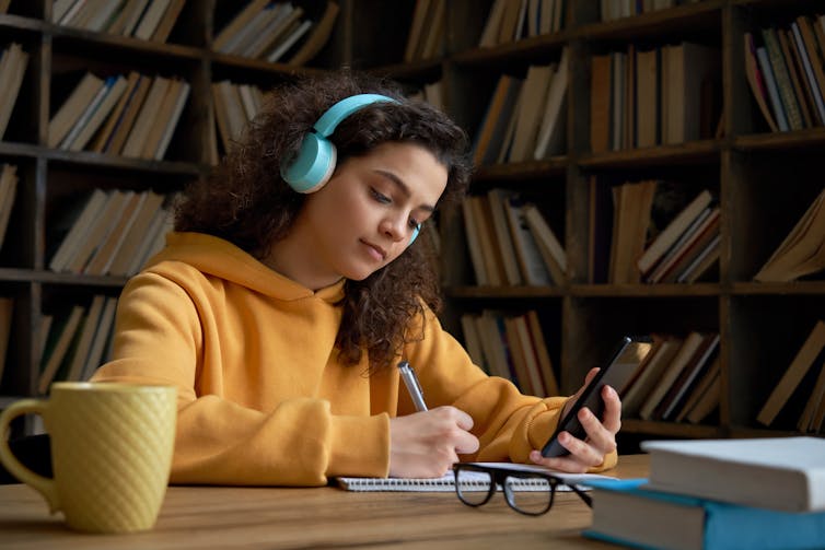 Girl in library taking notes from smartphone