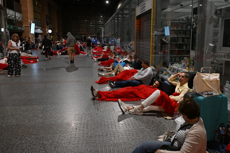 gens assis et allongés par terre dans une gare