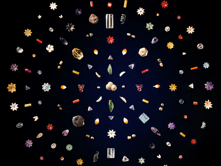Colourful gem stones laid in a circular pattern on a black background