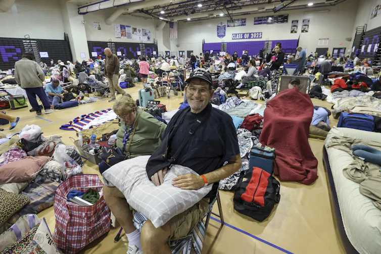 A man smiles at the camera from a crowded school gym
