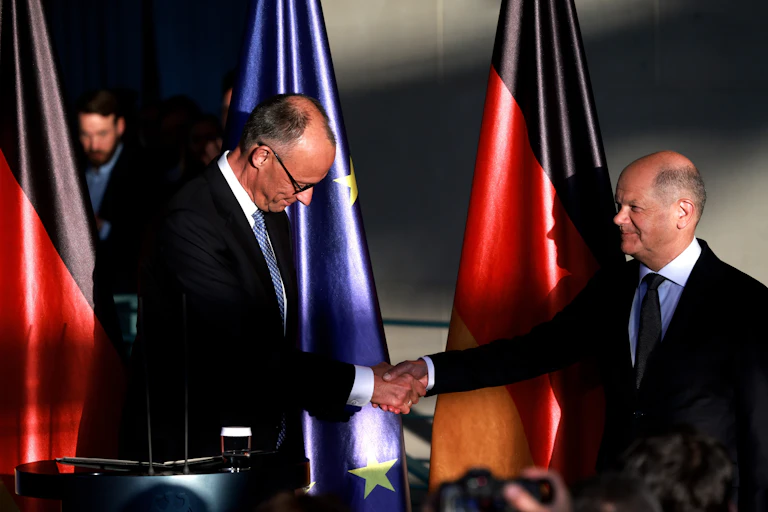 Friedrich Merz and Olaf Scholz shaking hands.