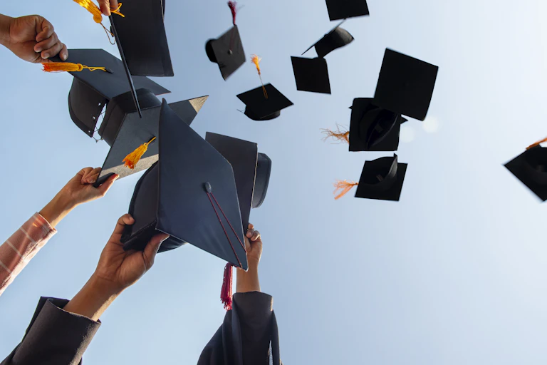 A cropped photo shows mortarboards being thrown into the sky.
