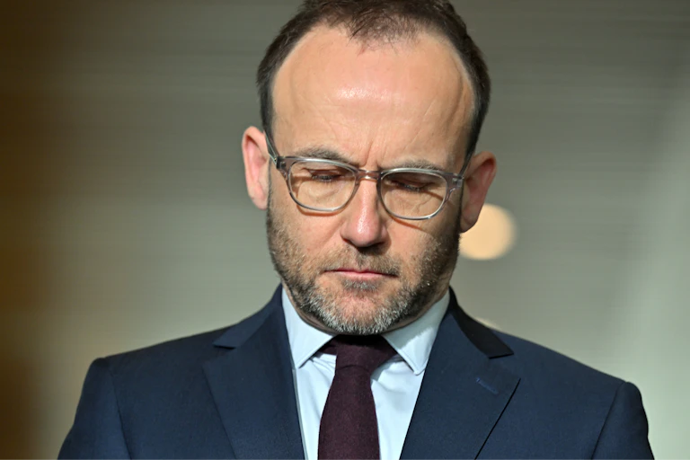 Downcast Adam Bandt in dark suit and tie