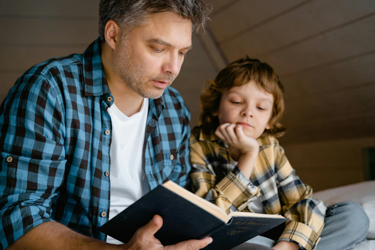 A man reads a book to a young boy.