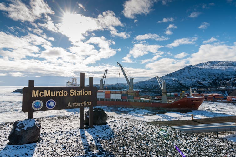 A ship near shore with a sign reading 'McMurdo Station'.
