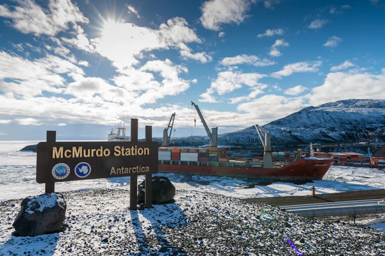 A ship near shore with a sign reading 'McMurdo Station'.