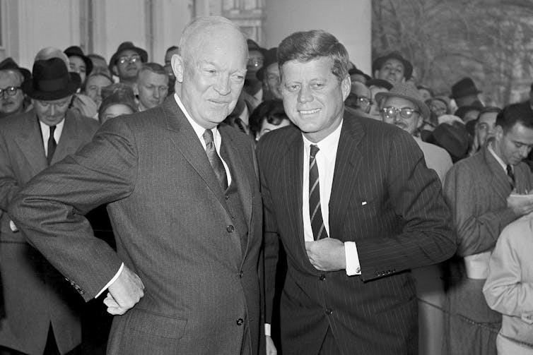 A black and white photo of two men in suits, smiling.
