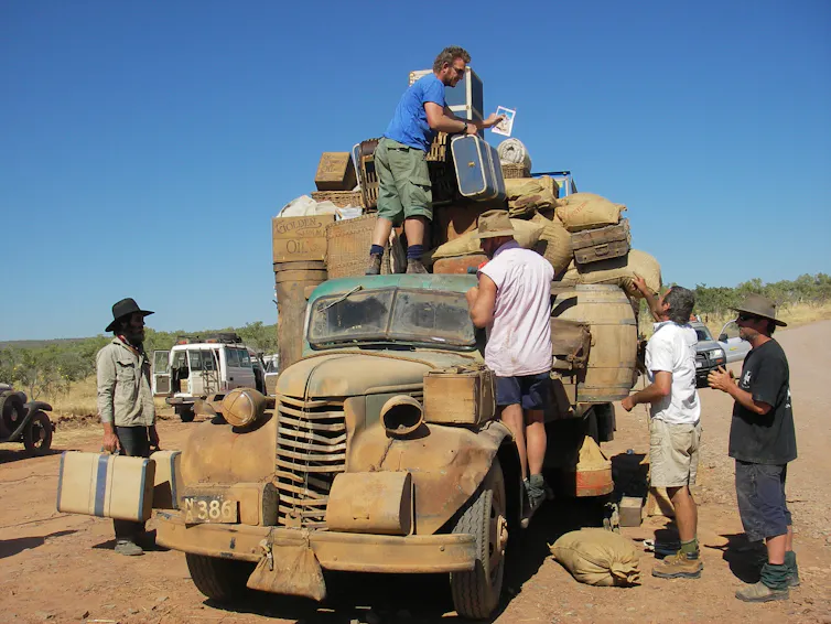 Men load suitcases on a dusty truck