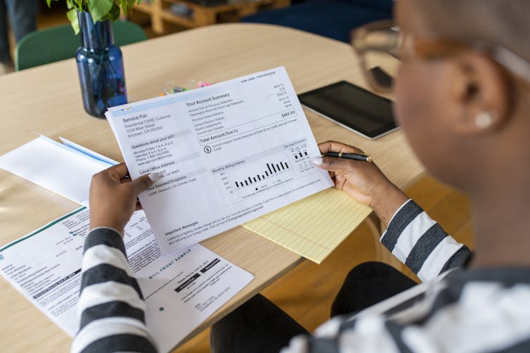 Over shoulder photo of woman looking at a utility bill