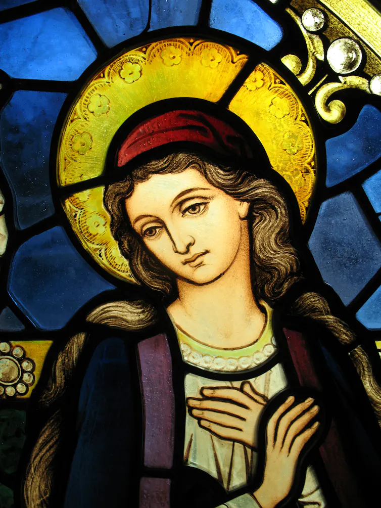A painting of the Virgin with eyes downcast and a halo around her head.