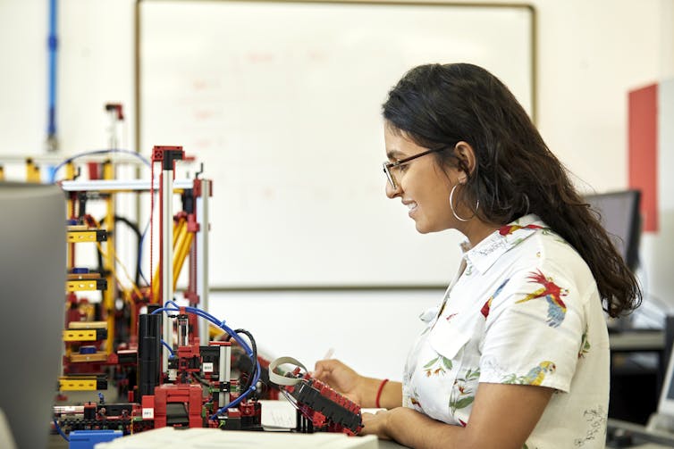 A female student with glasses looks at an engineering model.