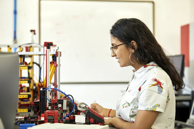 A female student with glasses looks at an engineering model.